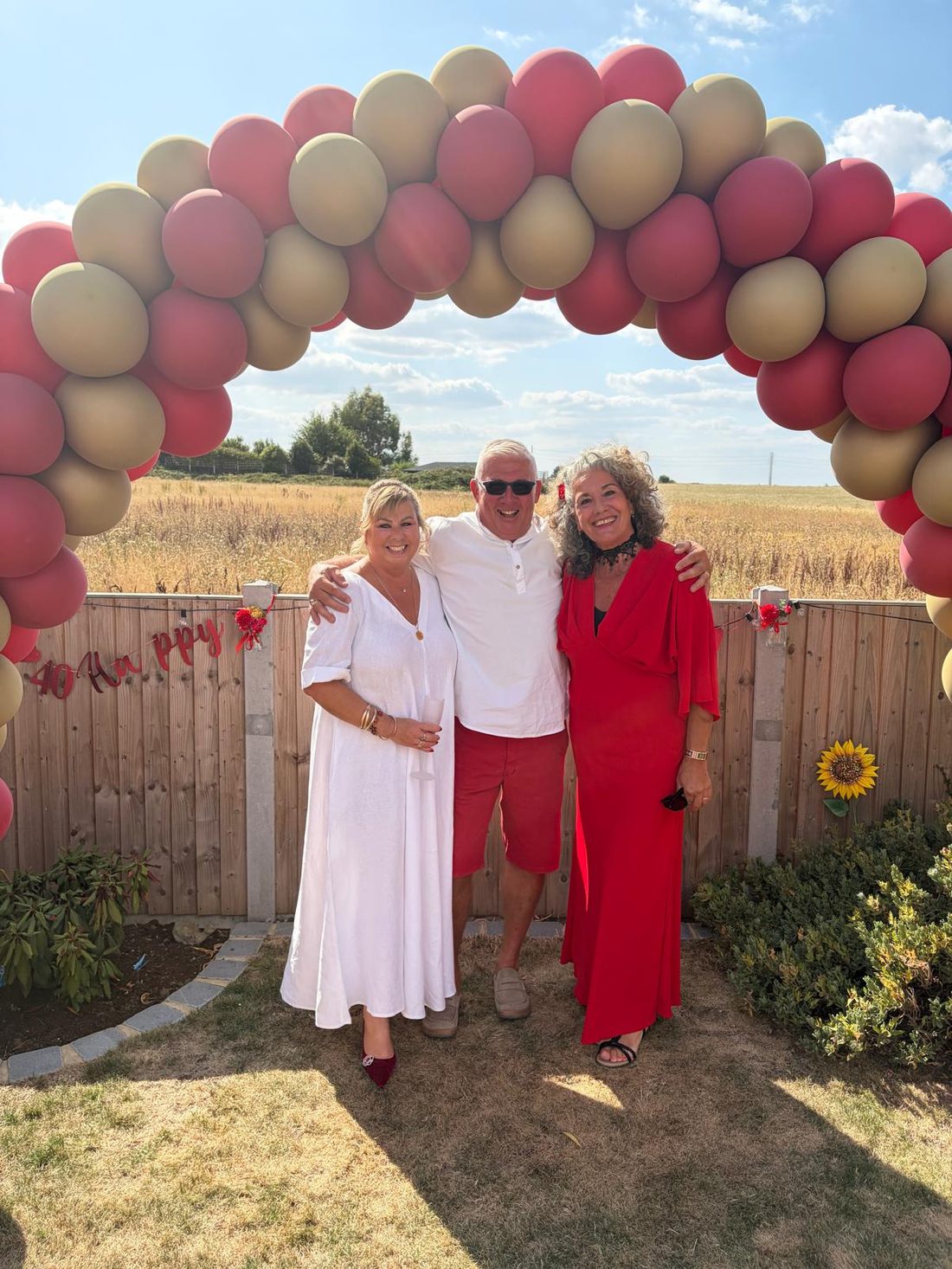Leah with a couple under a balloon arch